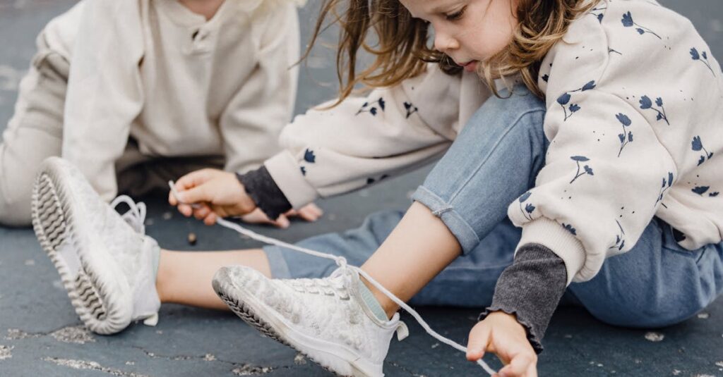 A young girl sits outdoors tying her shoelaces, enjoying a carefree moment.