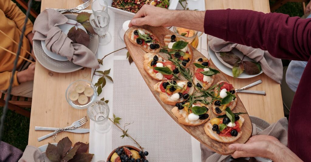 A lively outdoor meal gathering with a diverse array of dishes on a wooden table.