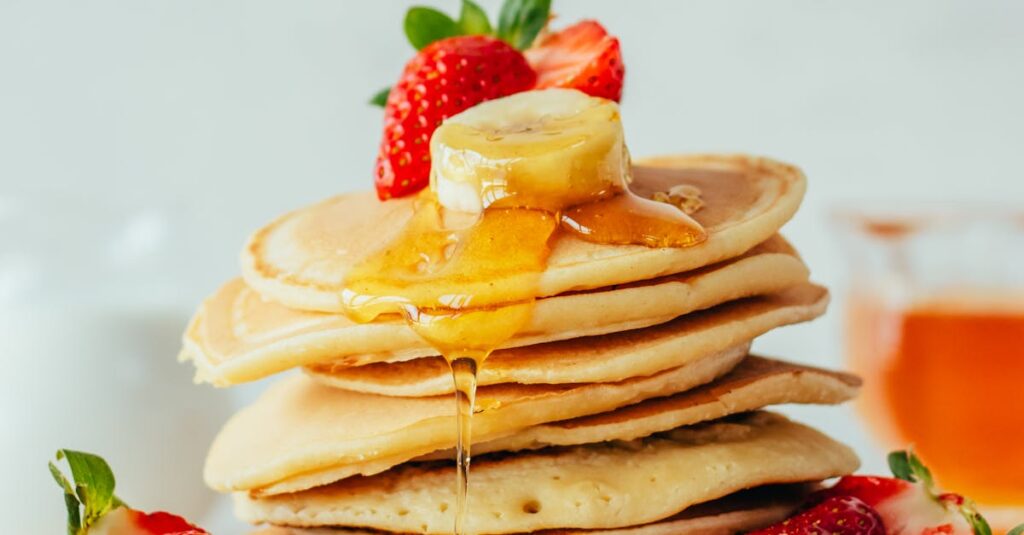 pexels-photo-30892986-30892986 Stack of fluffy pancakes with strawberries, banana slices, and honey. Perfect breakfast treat.